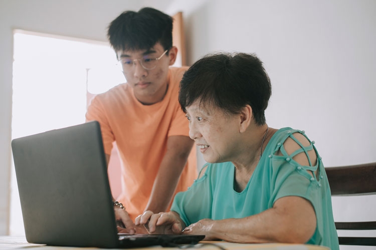 A grandson helping his grandmother on her computer