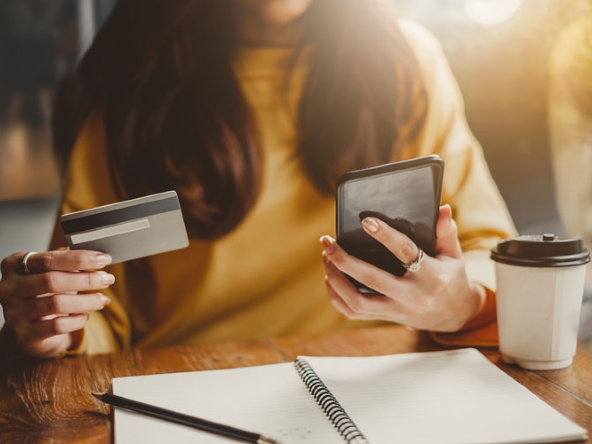 A woman holding a credit card in one hand and her phone in the other