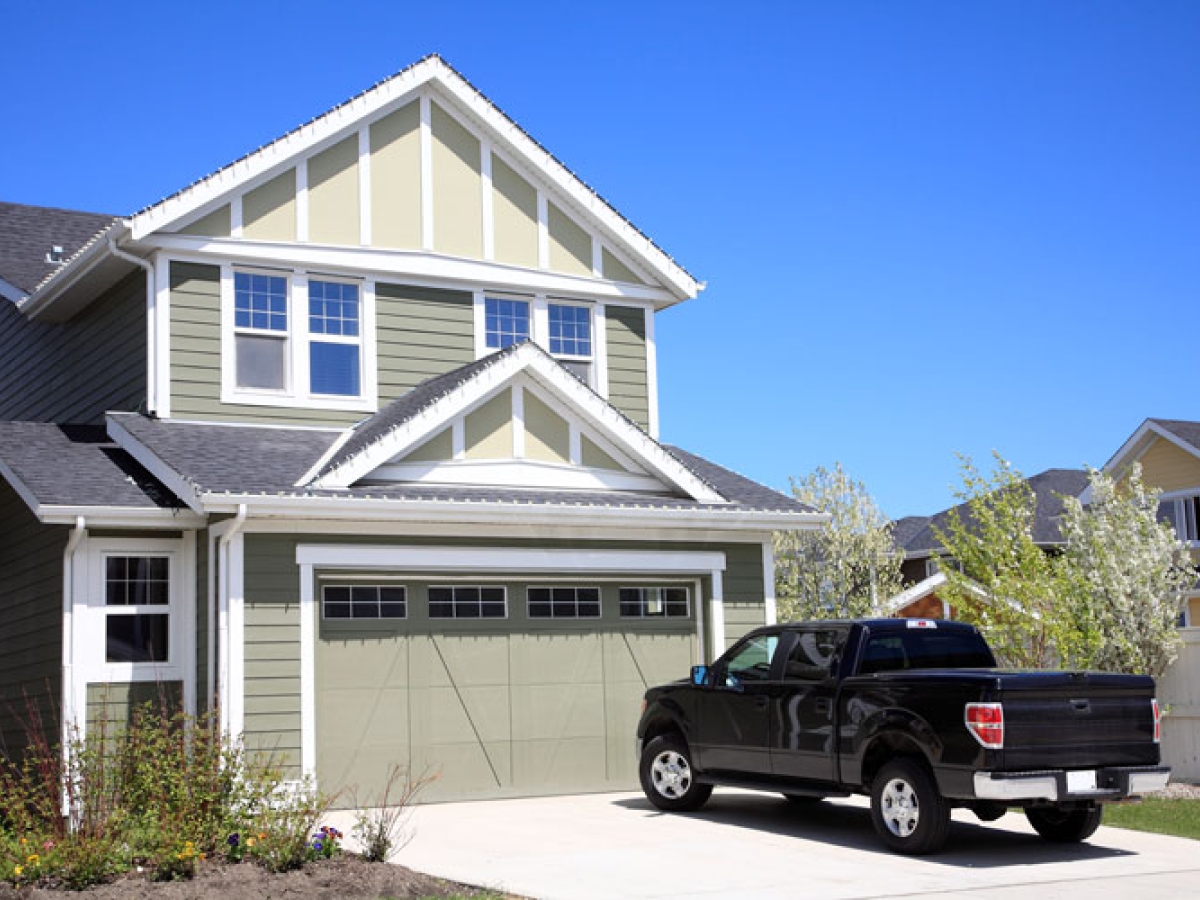 A grey house with a black truck parked in the driveway