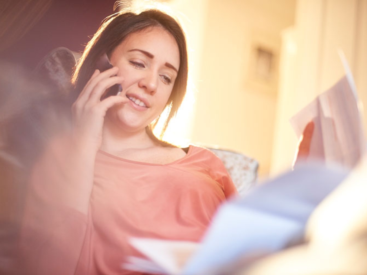A woman looking at her bills while speaking on the phone 